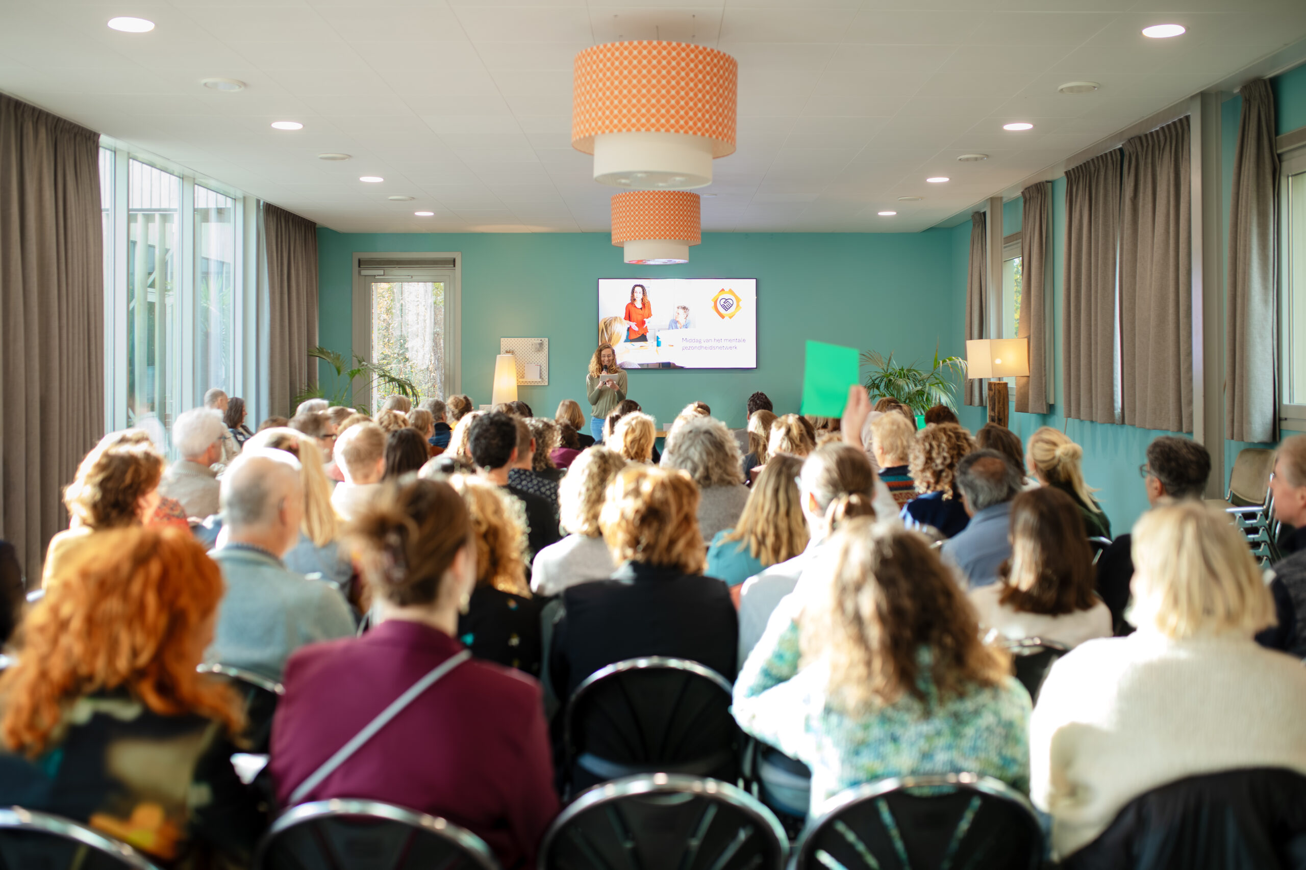 Mensen luisteren in een zaal naar een spreker
